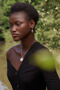 Load image into Gallery viewer, Woman wearing a black top with a blurred natural background
