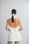 Load image into Gallery viewer, Woman wearing a white dress with a bow at the back on a plain background
