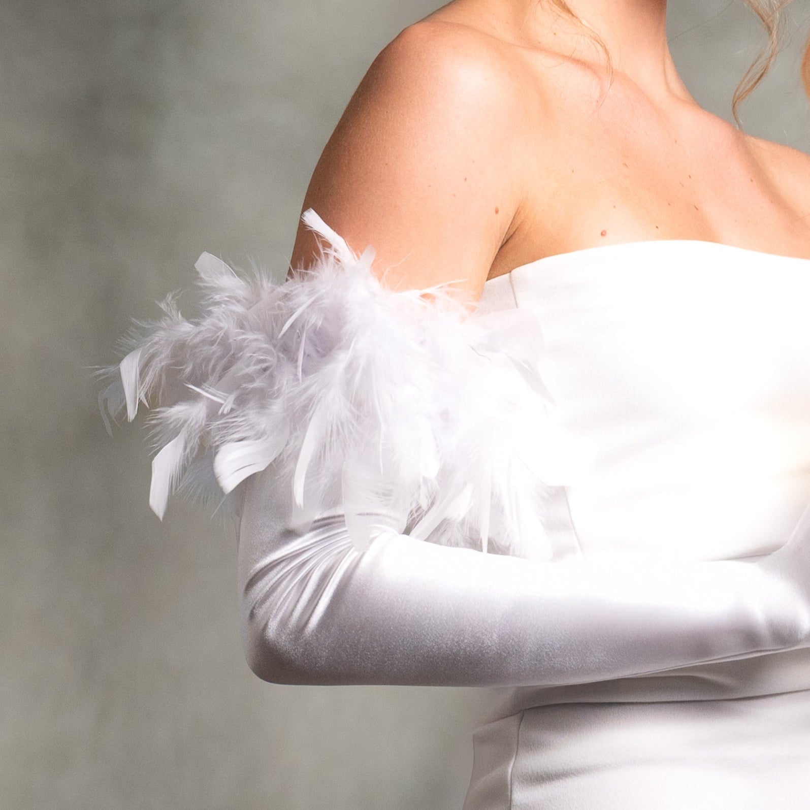 White off-shoulder dress with feather details on a neutral background