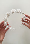Load image into Gallery viewer, White floral headband held by hands against a light gray background
