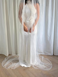 Load image into Gallery viewer, Person wearing a white wedding dress with a long pearl veil against a plain background
