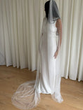 Load image into Gallery viewer, Person wearing a white wedding dress with a long pearl veil against a plain background
