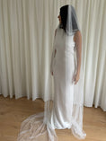 Load image into Gallery viewer, Person wearing a white wedding dress with a long pearl veil against a plain background
