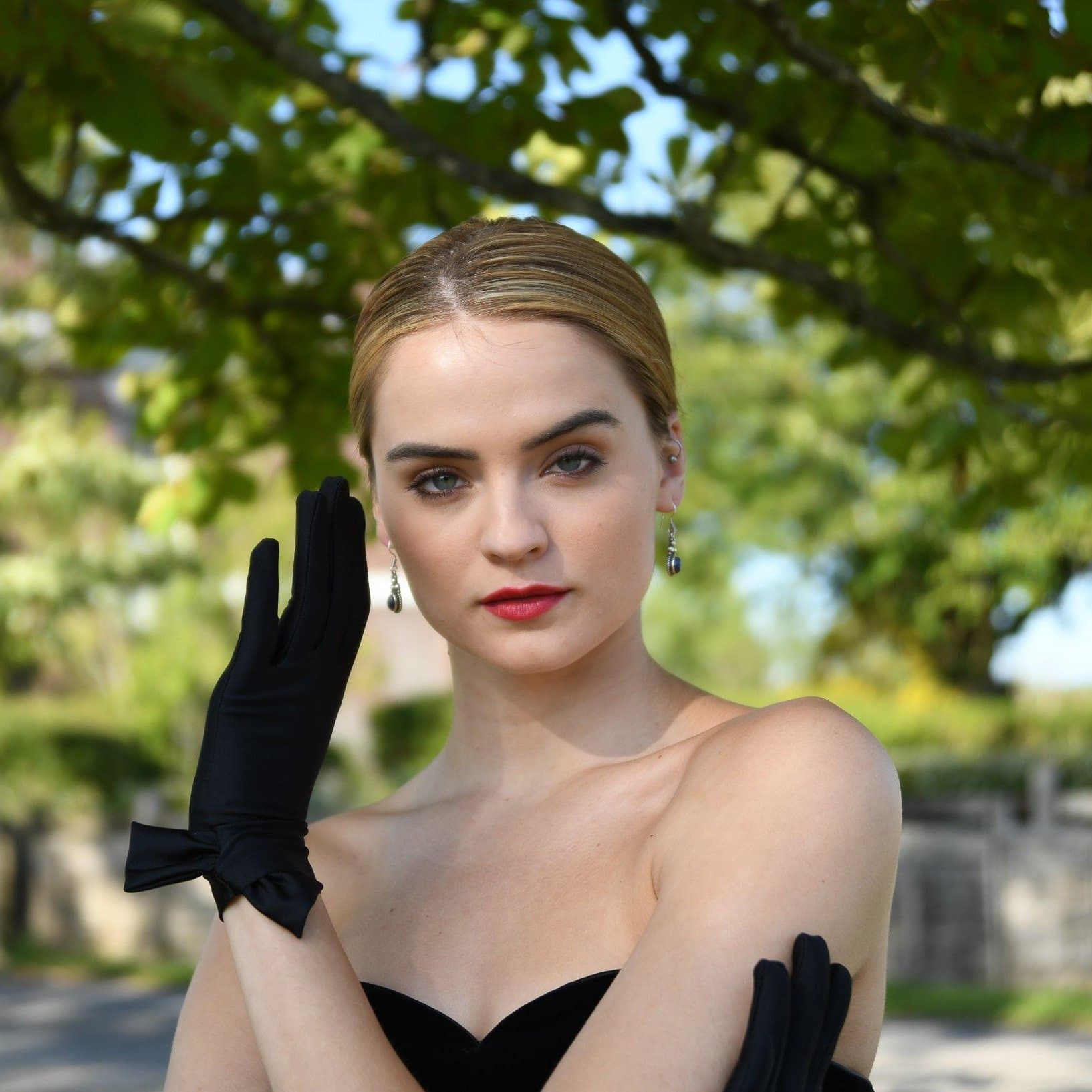 woman wearing Cornelia James black short satin bridal gloves with a side bow detail.