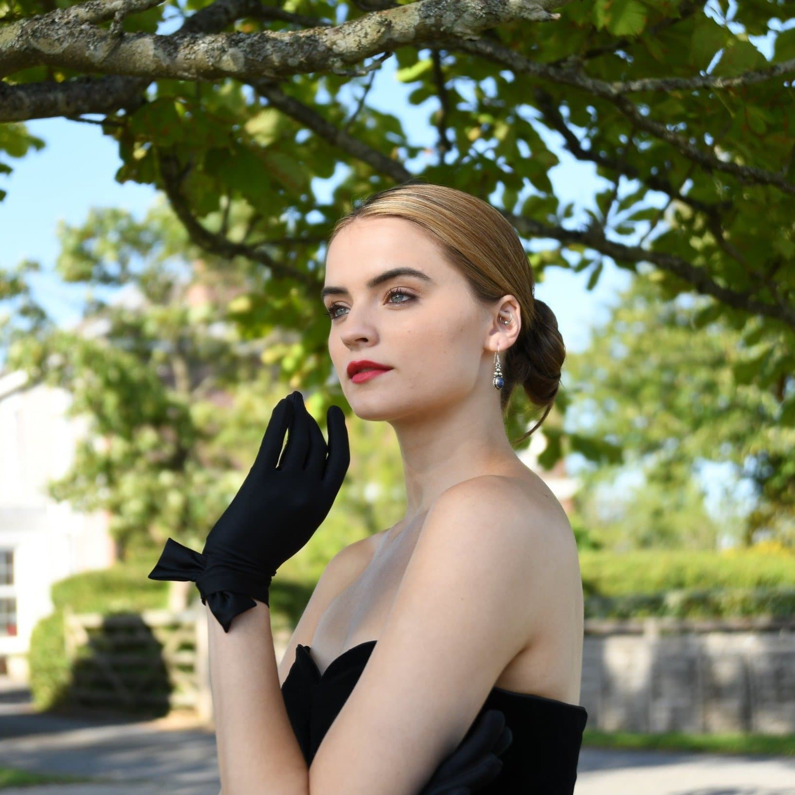 woman wearing Cornelia James short black satin bridal gloves with a side bow detail