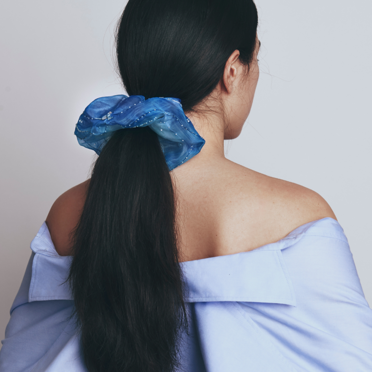 Person with a blue bridal scrunchie in their hair against a plain background