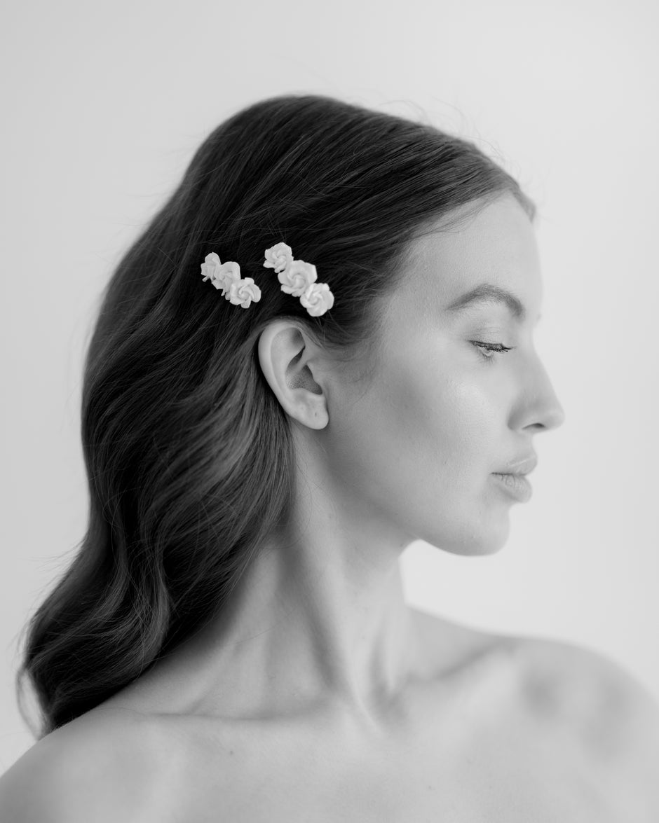 Woman with floral hair clips in her hair against a plain background