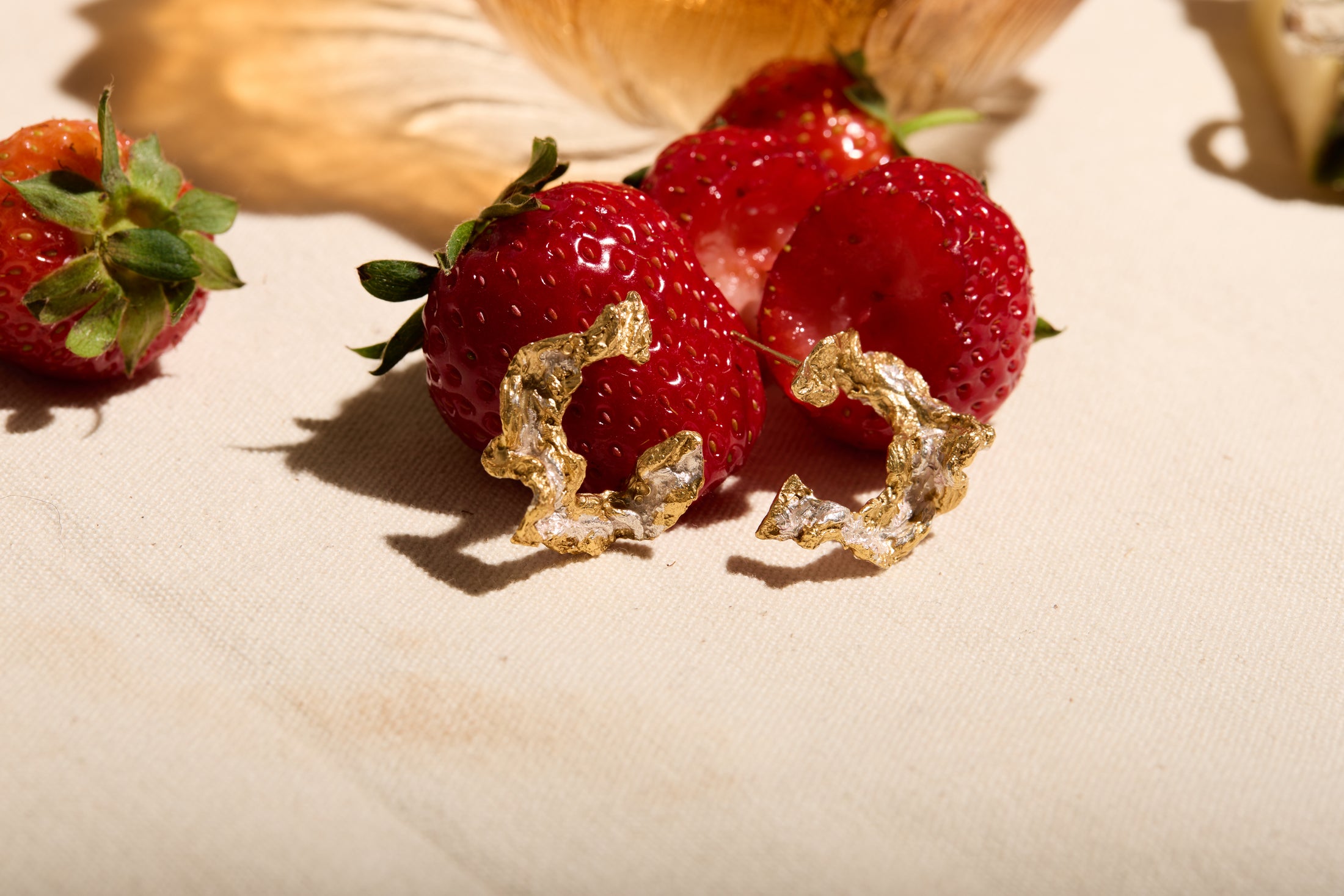 Strawberries with gold leaf on a beige surface