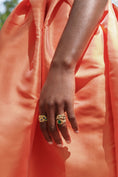 Load image into Gallery viewer, Hand wearing two rings with a bright orange background
