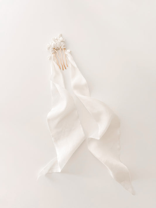 White satin ribbon with gold hair clips on a white background