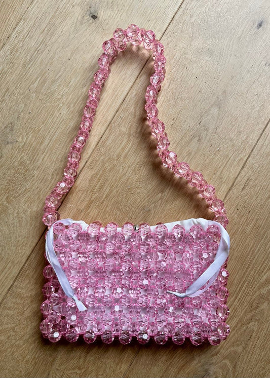 Pink beaded bridal handbag on a wooden surface