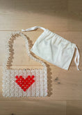 Load image into Gallery viewer, Clear bridal handbag with red heart design and white apron on a wooden surface
