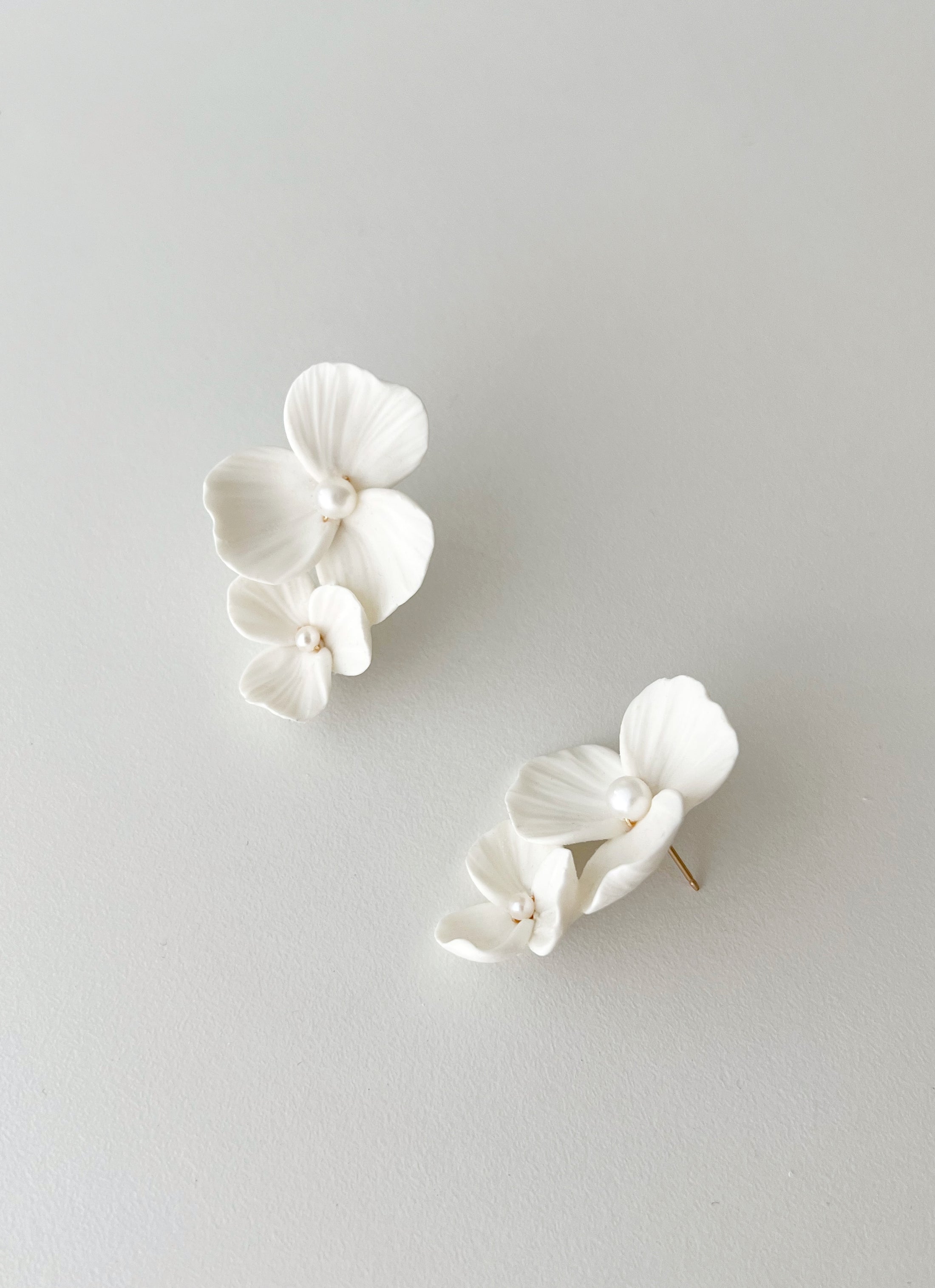 White orchid-shaped earrings on a light gray background