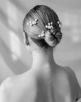 Load image into Gallery viewer, Person with a stylish hair bun adorned with flowers against a neutral background
