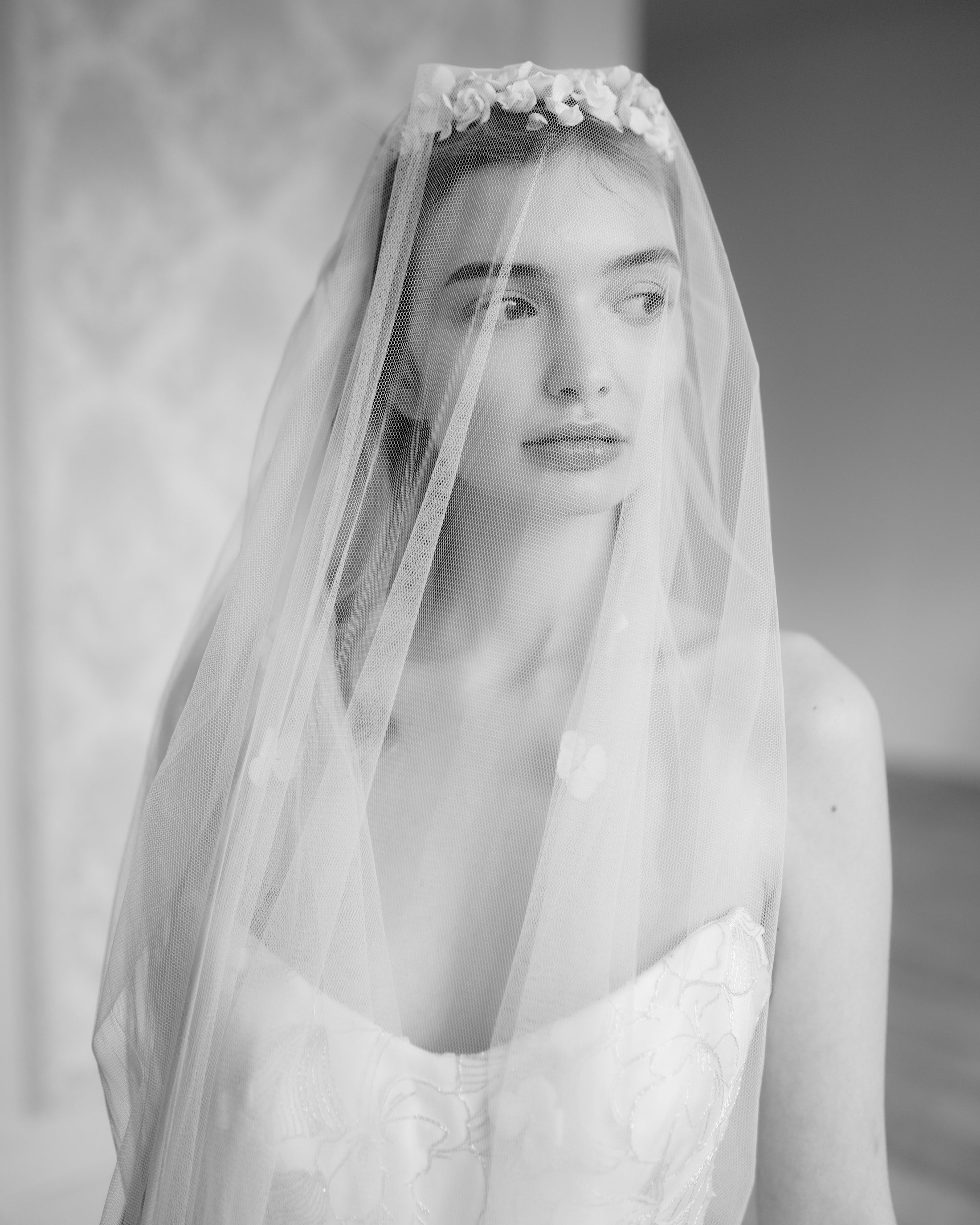 Black and white photo of a woman wearing a floral headband and veil.