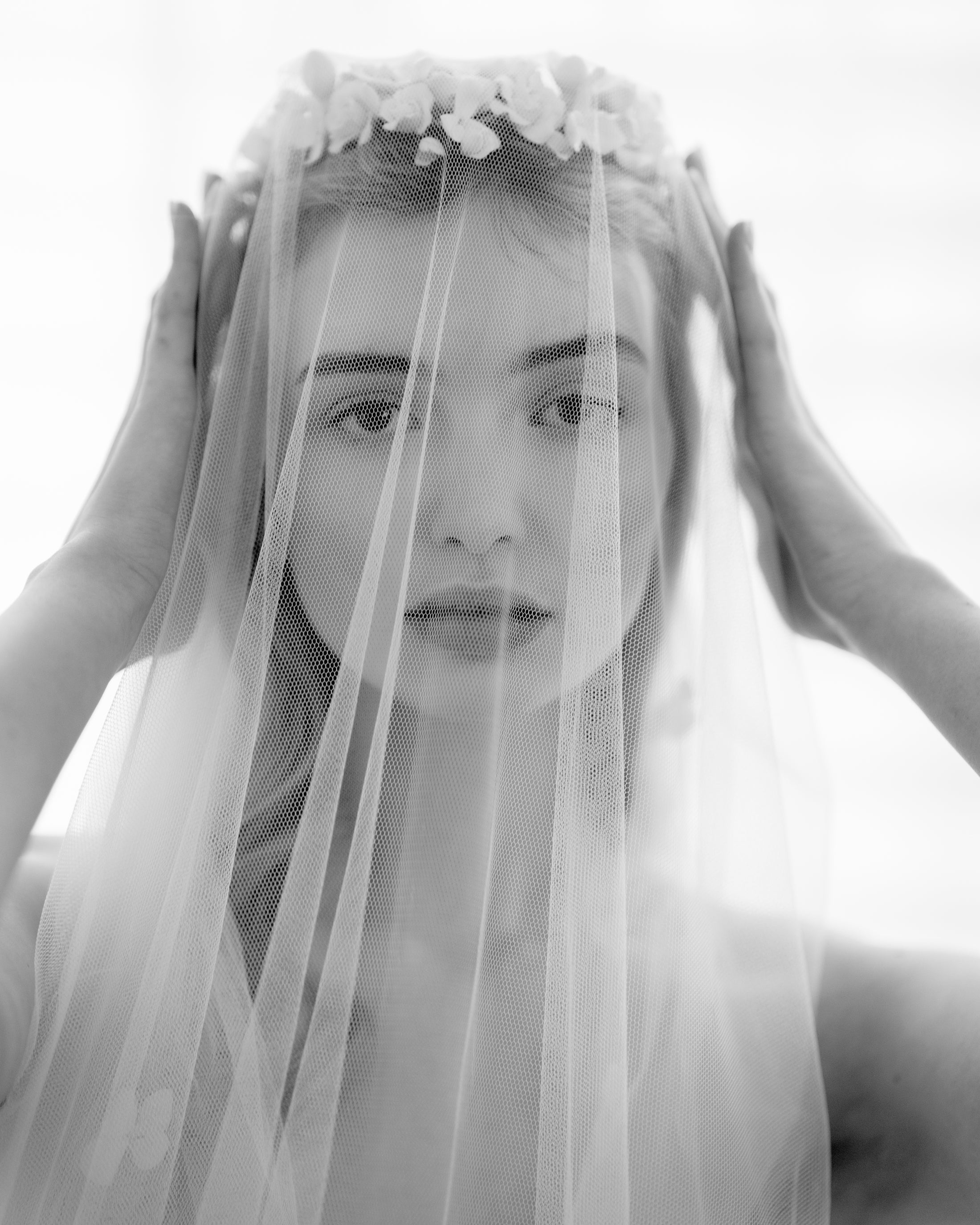 Black and white photo of a woman wearing a veil with floral accents.