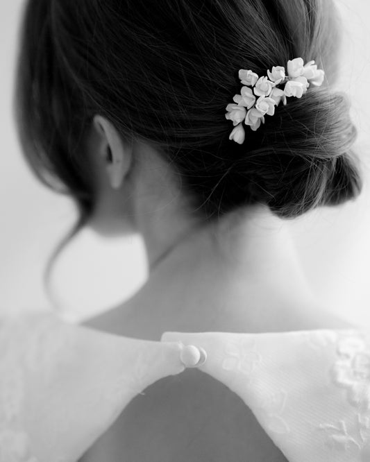 Black and white photo of a person with a floral hair accessory.