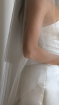 Load image into Gallery viewer, Bride wearing a white wedding dress with a plain veil against a white curtain background.
