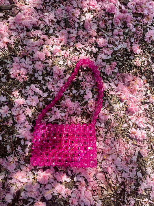 Pink beaded bridal handbag on a bed of pink flowers