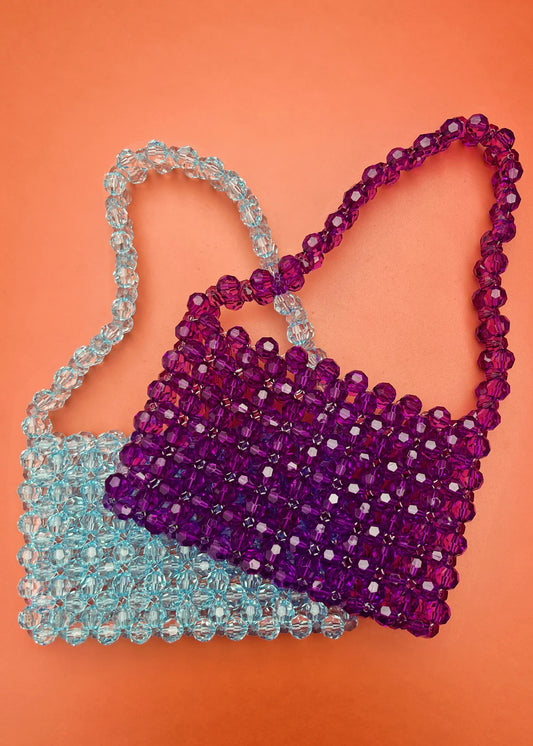 Two beaded bridal handbags, one purple and one blue, on an orange background