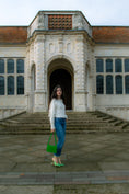 Load image into Gallery viewer, Woman holding a green bridal handbag in front of a large stone building
