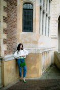 Load image into Gallery viewer, Woman standing against a stone wall of a building holding a green beaded bridal handbag
