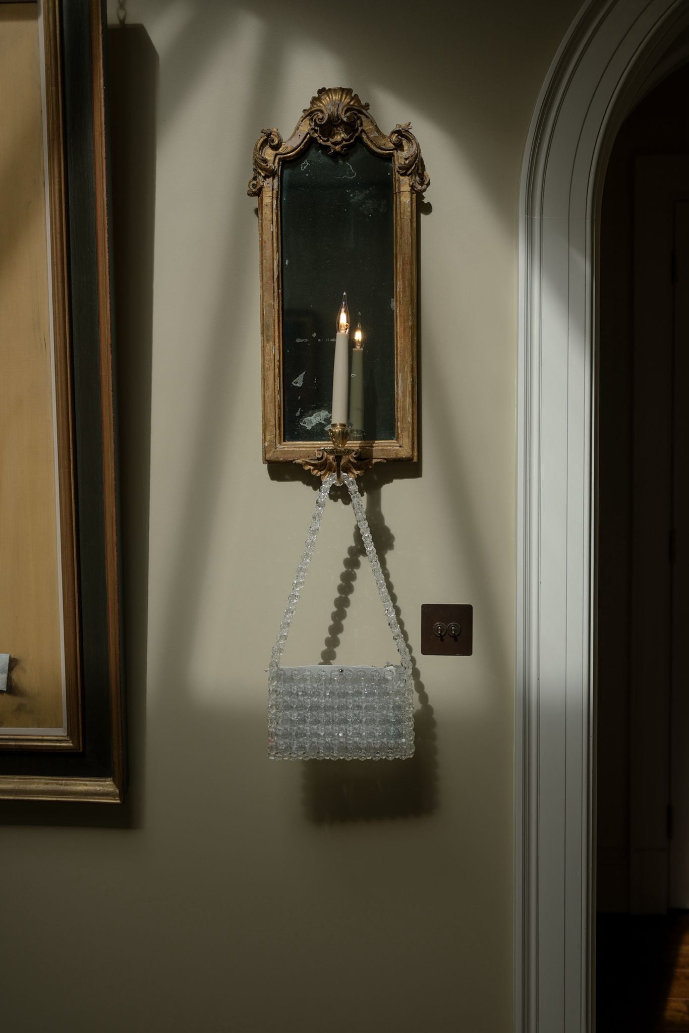 Decorative mirror with a candle and a beaded bridal bag on a wall 