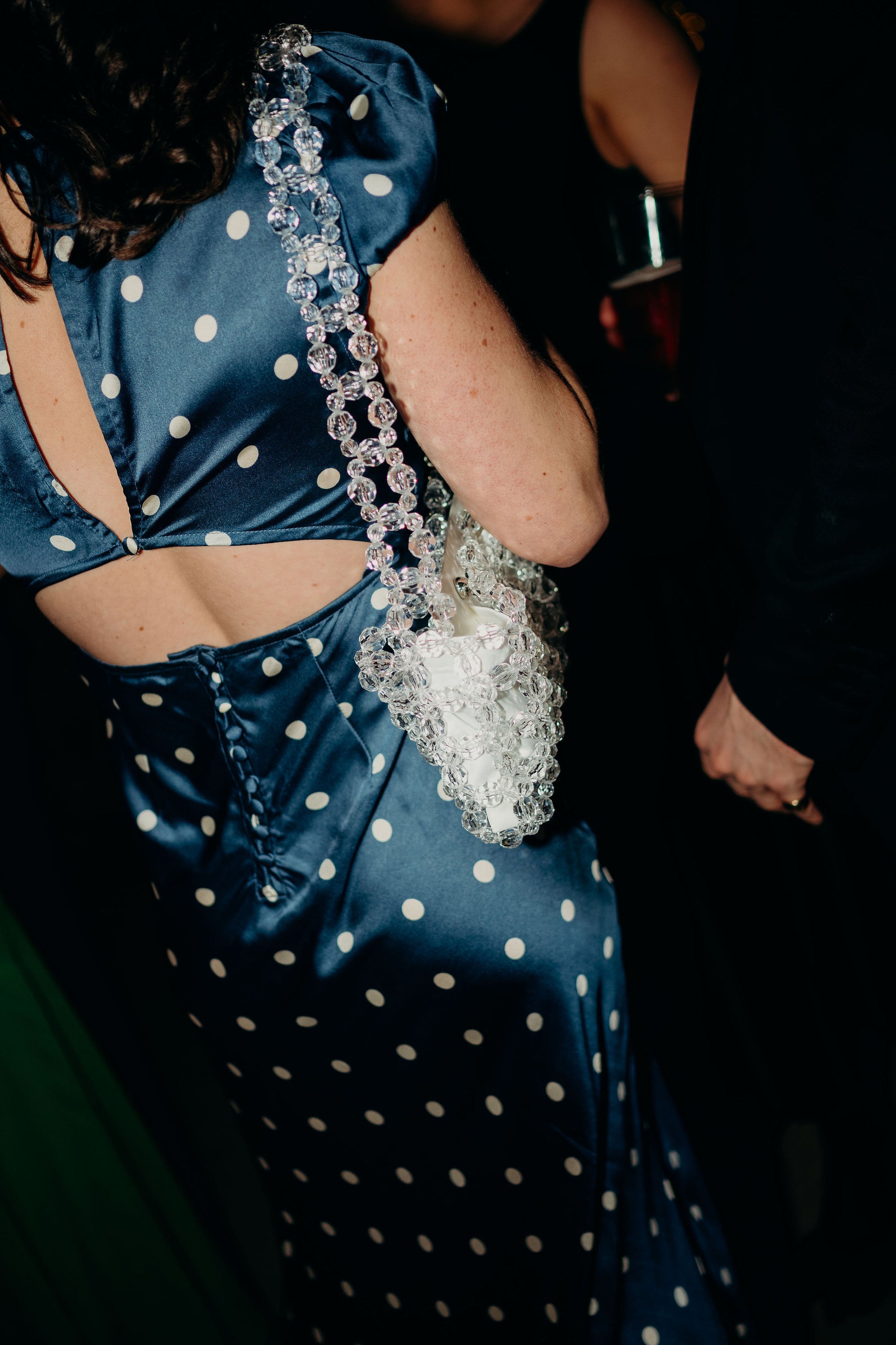 woman wearing a navy polkadot dress wearing a bridal bag