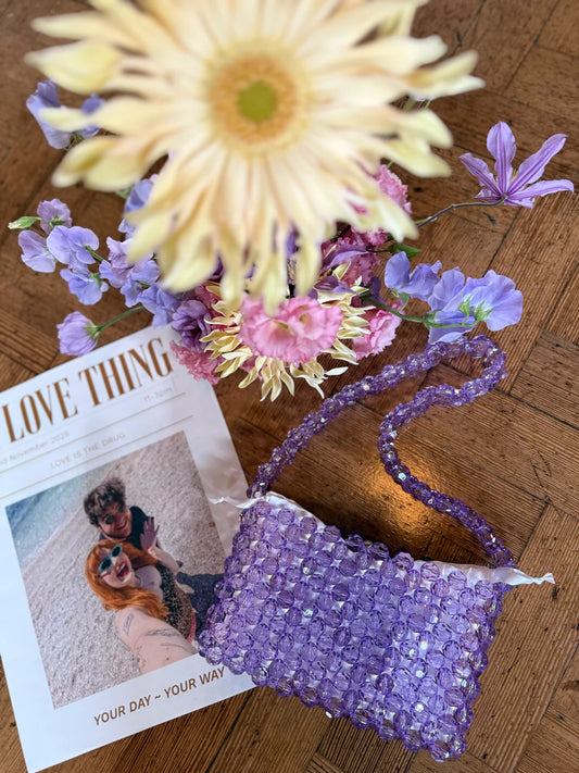 Purple beaded bridal bag with flowers and a photo on a wooden surface