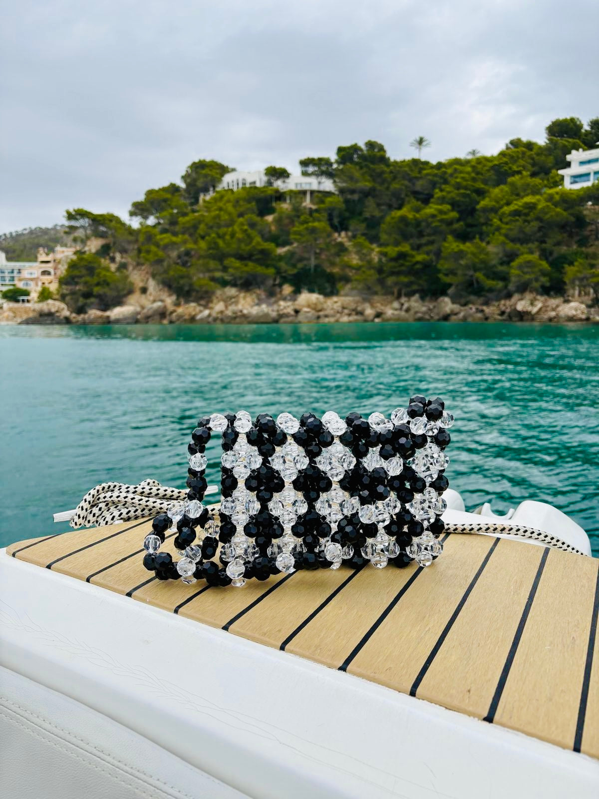 Black and white patterned bridal bag on a boat with a scenic background of water and trees.