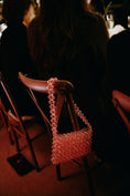 Load image into Gallery viewer, Pink beaded bridal bag on a chair with people in the background
