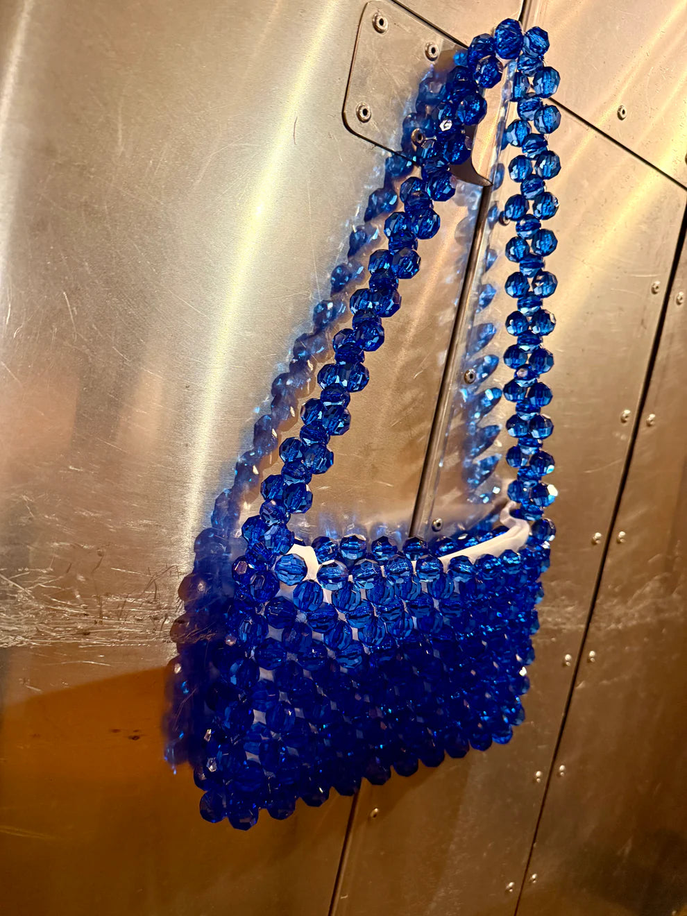 Blue beaded bridal bag on a metallic surface