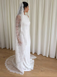 Load image into Gallery viewer, Woman wearing a white lace veil and wedding dress against a white curtain background

