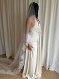 Load image into Gallery viewer, Bride wearing a white wedding dress with a lace veil against a white curtain background.
