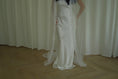 Load image into Gallery viewer, Person wearing a white wedding dress with a long veil in front of white curtains.

