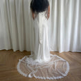 Load image into Gallery viewer, Person wearing a white wedding dress with a wedding veil in front of white curtains.

