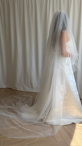 Load image into Gallery viewer, Person wearing a white wedding dress with a long veil against a plain background
