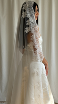 Load image into Gallery viewer, Bride wearing a white wedding dress with a lace veil against a white curtain background.
