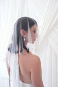 Load image into Gallery viewer, A bride shown from the back and side wearing a sheer white tulle bridal veil with delicate bead and sequin embellishments, paired with a white wedding dress against a soft white draped backdrop.
