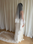 Load image into Gallery viewer, Bride wearing a white wedding dress with a lace veil against a white curtain background.
