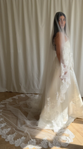 Load image into Gallery viewer, Bride wearing a white wedding dress with a lace veil against a white curtain background.

