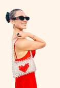 Load image into Gallery viewer, Woman in a red dress with a white bead bridal bag featuring a red heart design, wearing black sunglasses.
