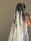 Load image into Gallery viewer, A long white lace bridal veil worn by a model, shown from the back against a plain beige wall.
