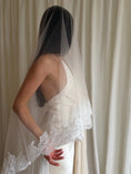 Load image into Gallery viewer, person in a wedding dress with a long lace trim veil against a curtain backdrop.
