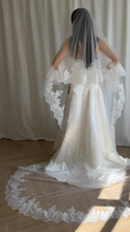 Load image into Gallery viewer, Bride wearing a white wedding dress with a lace veil against a white curtain background.
