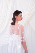 Load image into Gallery viewer, A young girl modeling a short white slip dress with a tulle petal bridal cape and white pointed-toe heels, standing against a draped white fabric backdrop.
