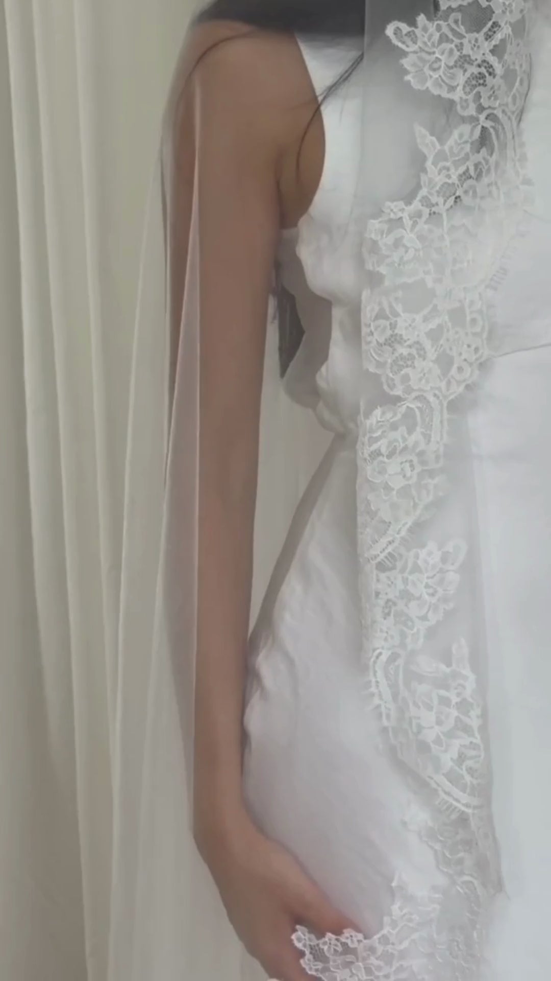 Model wearing White lace veil and wedding dress on a wooden floor with a plain white wall background