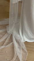 Load and play video in Gallery viewer, Person wearing a white wedding dress with a long pearl veil against a plain background
