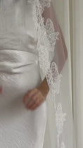Load and play video in Gallery viewer, White lace veil and wedding dress on a wooden floor with a plain white wall background
