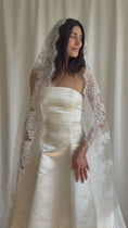 Load and play video in Gallery viewer, Bride wearing a white wedding dress with a lace veil against a white curtain background.

